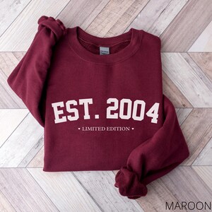 May include: Maroon sweatshirt with white text that reads "EST. 2004" and "LIMITED EDITION".