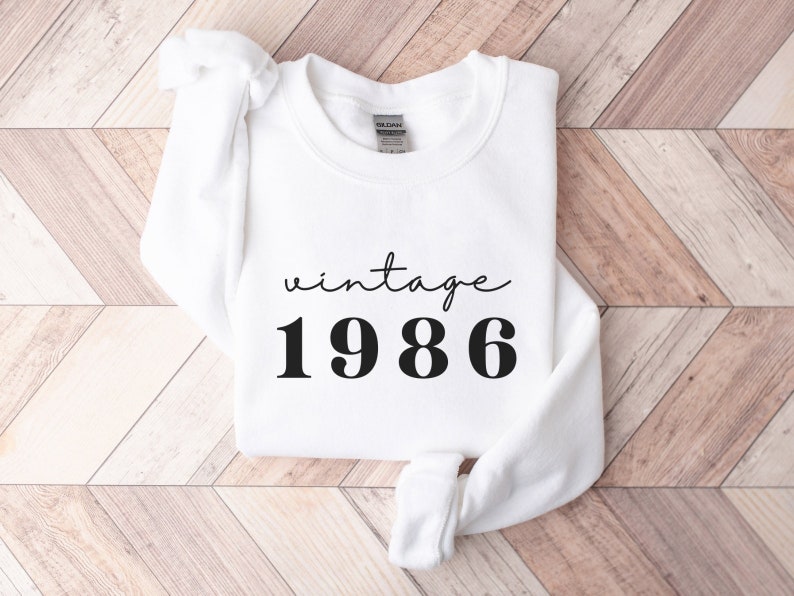 May include: White sweatshirt with black text that reads "vintage 1986".