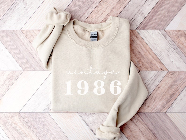 May include: A beige sweatshirt with the text "vintage 1986" printed in white.
