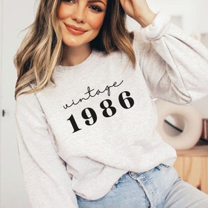 May include: A gray sweatshirt with the text "vintage 1986" printed on the front.