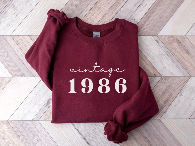 May include: Burgundy sweatshirt with the text "vintage 1986" in white.