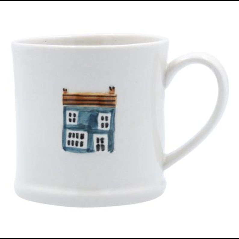May include: White ceramic mug with a blue and brown illustration of a house on the front.