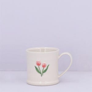 May include: White ceramic mug with a pink tulip design.