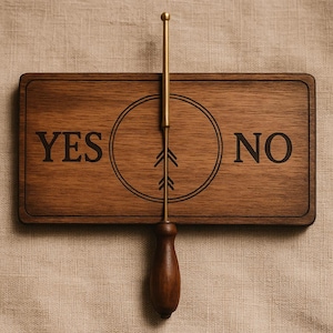 Può includere: Una tavola divinatoria in legno con le parole "YES" e "NO" ai lati di un disegno circolare con frecce. Un puntatore in ottone e legno poggia sulla tavola, pronto a rispondere alle domande. La tavola è in legno scuro.