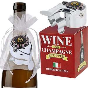 May include: A chrome wine and champagne stopper featuring a decorative top with a black, yellow, and pink floral pattern. The stopper is packaged in a red box labeled WINE AND CHAMPAGNE STOPPER DESIGNED IN ITALY with an Italian flag icon.