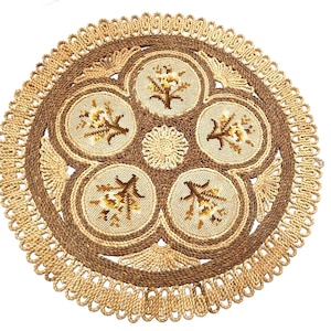 May include: A round, woven fiber doily featuring a central floral motif surrounded by five circular panels, each embroidered with a brown and yellow flower design. The piece is finished with a decorative, looped braided border in light tan.