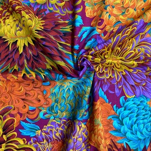 May include: A vibrant fabric with a floral pattern featuring large, colorful chrysanthemums in shades of purple, blue, orange, and yellow. The background is a deep burgundy color.