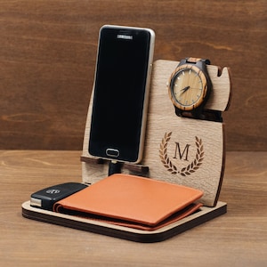 Può includere: Organizzatore in legno con un supporto per telefono, un porta orologio e un portafoglio in pelle. L'organizzatore ha uno spazio per le chiavi e un'iniziale "M" personalizzata incisa sul davanti.