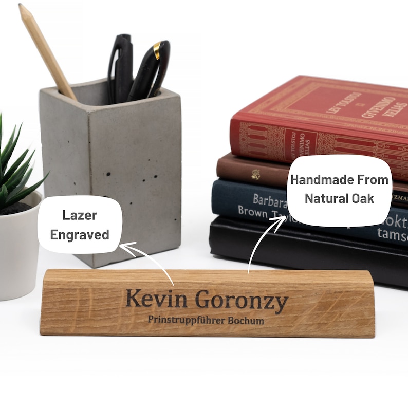Op de afbeelding: Een houten bureau naamplaatje met de tekst "Kevin Goronzy" en "Prinstruppf&uuml;hrer Bochum" gegraveerd in zwart. Het naamplaatje is gemaakt van natuurlijk eikenhout en is handgemaakt.