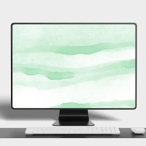 May include: A black computer monitor with a green watercolor background on the screen. A white keyboard and a white mouse are on a black desk in front of the monitor.
