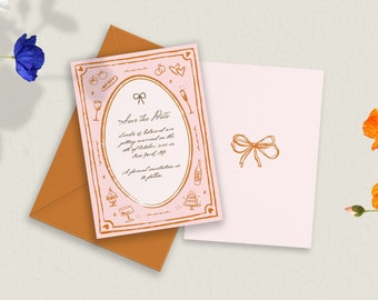 Pode incluir: Um convite de casamento rosa claro com um laço dourado e uma borda decorativa. O convite inclui o texto "Save the Date" e outros detalhes. Um envelope e um cartão correspondente também estão presentes, com detalhes florais.