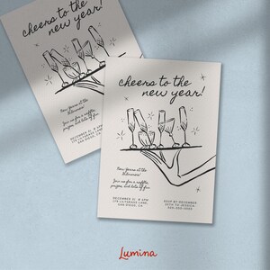 Może przedstawiać: Czarno-biała ilustracja kieliszk&oacute;w do szampana na tacy z tekstem "Cheers to the new year!"  Sylwester w Filmoreal. Dołącz do nas na loterii, nagr&oacute;d i mn&oacute;stwo zabawy. 31 grudnia, 20:00, 179 Lilygrass Lane, San Diego, CA. RSVP do 20 grudnia do Jessici, 305-555-5555. Lumina.