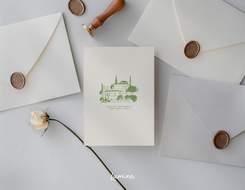 May include: A white card with a green illustration of a building with trees and the text "Villa del Balbianello, Lake Como, Italy". The card is surrounded by white envelopes with wax seals.