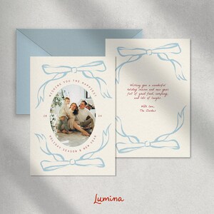May include: A Christmas card with a blue and white illustration of a bow and a family photo inside. The text reads "Wishing you the happiest holiday season & new year 2024".