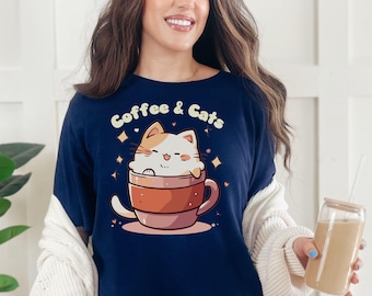 May include: Navy blue long-sleeve shirt featuring a cartoon cat in a coffee cup with the text "Coffee & Cats". The cat is white and orange. The coffee cup is brown and pink. The shirt is made of a soft, comfortable material.