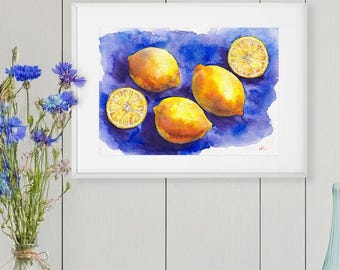 May include: A framed watercolour painting of lemons on a blue background hangs above a wooden cabinet. The cabinet displays a vase of blue flowers, white candles, and blue glass vases. The scene is set against a white panelled wall.