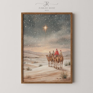 Puede incluir: Una impresión enmarcada que presenta una pintura a la acuarela de un paisaje invernal. La obra representa a tres figuras sobre camellos, viajando por un desierto nevado bajo un cielo estrellado, con una estrella brillante arriba. El marco es de color marrón cálido.