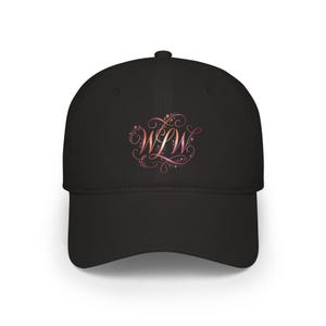 Può includere: Un cappellino da baseball nero con una grafica centrale che riporta le lettere WLW in un carattere corsivo stilizzato. La scritta presenta una sfumatura nei toni del rosa, arancione e rosso, circondata da intricati motivi floreali.