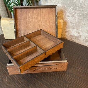 May include: A wooden box with a hinged lid and a removable tray. The tray has four compartments. The box is engraved with the text "you do not yield".