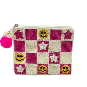 May include: A beaded clutch with a zipper closure and a pink tassel. The clutch features a checkerboard pattern of pink squares, cream squares, yellow smiley faces, and white star shapes.