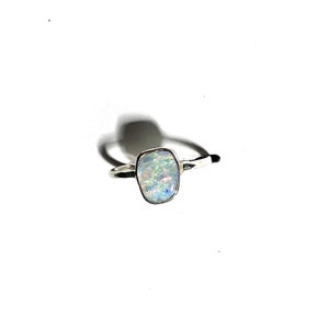 Peut inclure: Une bague en argent avec une pierre d'opale blanche. L'opale a une forme irrégulière et unique.