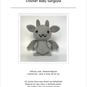 Op de afbeelding: Een gehaakte grijze baby-waterspuwer met rode ogen, vleugels en kleine hoorns. De tekst "Crochet Baby Gargoyle" staat bovenaan. De afmeting is ongeveer 15 cm hoog.