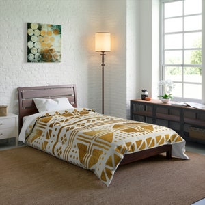 May include: A white and gold geometric patterned duvet cover on a bed with a wooden frame. The duvet cover has a modern, abstract design with gold accents.