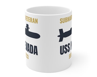 Puede incluir: Una taza de cerámica blanca con la silueta de un submarino en azul oscuro, texto dorado que dice VETERAN y SUBMARINE, y texto azul oscuro que dice NEVADA 733 y USS NEVADA SSN 733. El diseño está impreso en la superficie exterior de la taza.