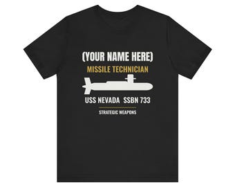 May include: A black short-sleeved t-shirt featuring a white silhouette of a submarine. The text reads (YOUR NAME HERE), MISSILE TECHNICIAN, USS NEVADA SSBN 733, and STRATEGIC WEAPONS in white and gold lettering centred on the chest area.