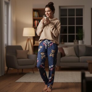 Op de afbeelding: Marineblauwe pyjamabroek met een teddybeerpatroon en witte stippen. De broek heeft een taille met trekkoord en wordt gecombineerd met een beige hoodie. Een comfortabele loungewear-optie.