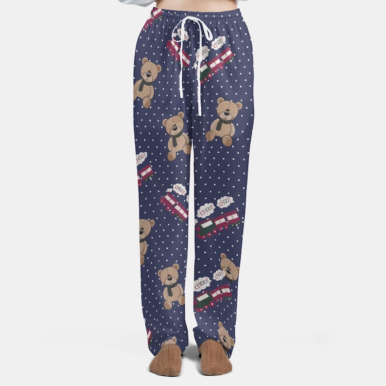 Op de afbeelding: Marineblauwe pyjamabroek met een wit stippenpatroon. De broek heeft een herhalend patroon van bruine teddyberen met groene sjaals en rode treinwagons met de tekst "Choo Choo". Het heeft een taille met trekkoord.