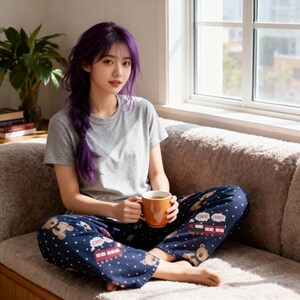 Op de afbeelding: Een persoon draagt een grijs t-shirt en een marineblauwe pyjamabroek met een teddybeer- en treinpatroon. De persoon houdt een bruine mok vast. Op de pyjamabroek staat de tekst "CHOO CHOO!". De persoon zit op een beige bank bij een raam.