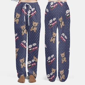 Op de afbeelding: Marineblauwe pyjamabroek met een herhalend patroon van teddyberen met sjaals, rode en groene treinen en witte stippen. De trein heeft het woord "choo" in een tekstballon. De broek heeft een taille met trekkoord.