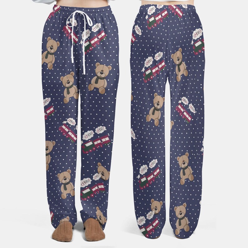 Op de afbeelding: Marineblauwe pyjamabroek met een herhalend patroon van teddyberen met sjaals, rode en groene treinen en witte stippen. De trein heeft het woord "choo" in een tekstballon. De broek heeft een taille met trekkoord.