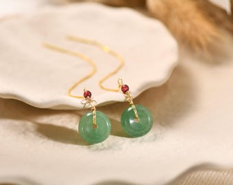 May include: A pair of gold dangle earrings with green jade stone circles and red gemstone accents.
