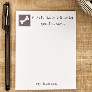 May include: White notepad with a black broken bone icon and the text "FRACTURED AND BROKEN ARE THE SAME."  The notepad also has the text "RAD TECH LIFE" at the bottom.