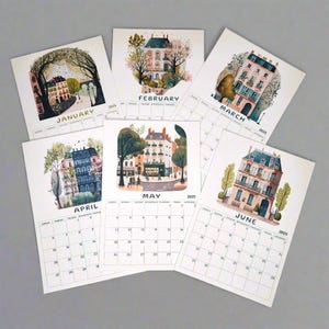 May include: A set of six illustrated calendar cards featuring Parisian scenes with buildings, trees, and streets. Each card has a different month of the year, from January to June, and the year 2025 printed on it.