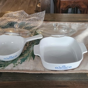 May include: Two blue and white casserole dishes with lids. The dishes have a floral design and the lids are made of glass.