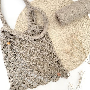 Peut inclure: Un sac cabas en crochet beige avec une anse tressée et un accent en perle de bois. Le sac est fait de fibres naturelles et a un tissage lâche et ouvert.