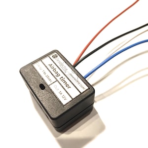 May include: Black airbag timer with a white label that reads "Airbag timer" and "Delay 1 to 25sec Out 1A 12V". The label also includes the company name "Deselettra" and website "deselettra.com".