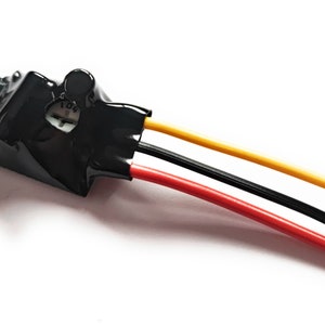 Può includere: Un componente elettrico nero con tre fili: rosso, nero e giallo. Il componente è rivestito di nastro isolante elettrico nero e ha il numero "104" stampato su di esso.