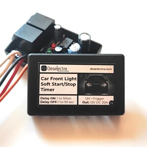 May include: A black electronic timer for car front lights, branded "Deselectra." The timer displays text detailing delay settings and voltage requirements. Various coloured wires protrude from the device, designed for automotive applications.