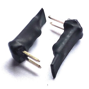 Può includere: Due connettori elettrici neri con puntali dorati. I connettori sono isolati con gomma nera.