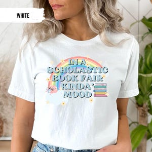 Puede incluir: Camiseta blanca con un arco&iacute;ris y el texto "In a Scholastic Book Fair Kinda' Mood".