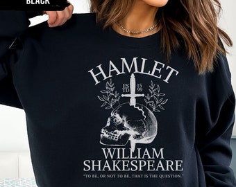 May include: Black sweatshirt with a white graphic design featuring a skull with a dagger through it. The text reads "Hamlet", "ES TD 15 99", "William Shakespeare", and "To be, or not to be, that is the question."