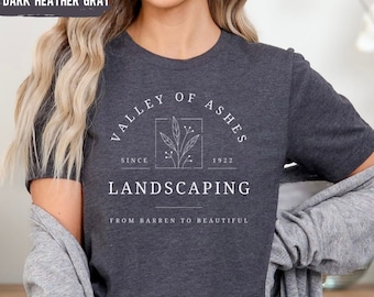 May include: Dark heather grey t-shirt with a white graphic design that says "Valley of Ashes Landscaping Since 1922 From Barren to Beautiful".