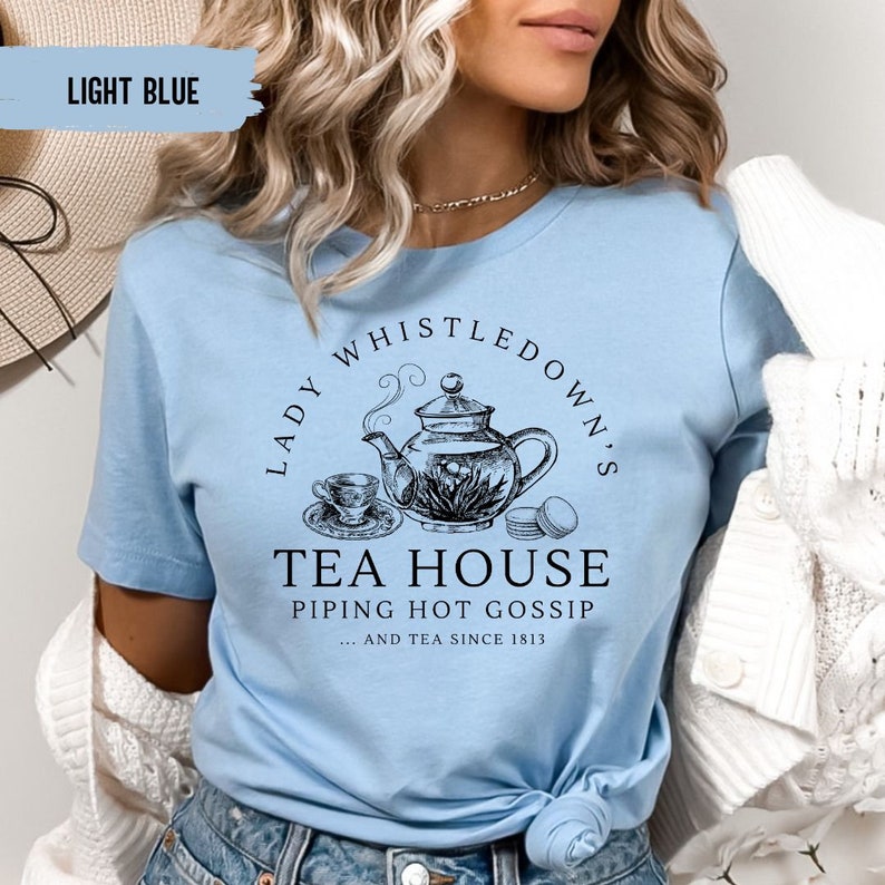 May include: Light blue t-shirt with a black and white illustration of a teapot, teacup, and macarons. The text reads "Lady Whistledown's Tea House Piping Hot Gossip...and Tea Since 1813"