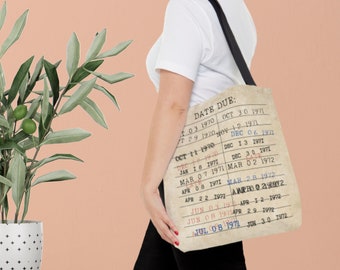 May include: A beige canvas tote bag with a vintage library card design. The bag features a date due list with dates from October 1970 to June 1972.