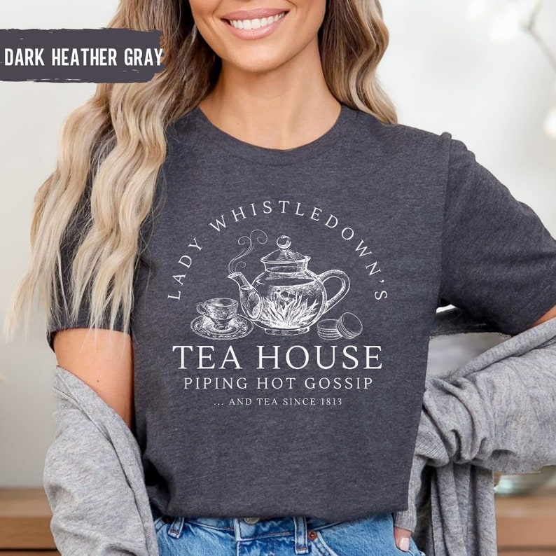 May include: Dark heather gray t-shirt with a white graphic of a teapot and the text "Lady Whistledown's Tea House Piping Hot Gossip...and tea since 1813."