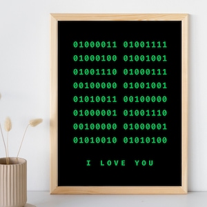 Könnte beinhalten: Ein gerahmter Schwarzweißdruck mit grünem Text. Der Text lautet "01000011 01001111 01000100 01001001 01001110 01000111 00100000 01001001 01010011 00100000 01000001 01001110 00100000 01000001 01010010 01010100 ICH LIEBE DICH".